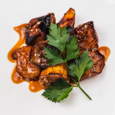 Grilled Egplant garnished with fresh herb leaf.