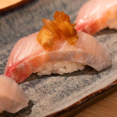 Amberjack nigiri sushi with glazed garnish.