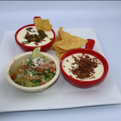 Platter with three dips and a side of tortilla chips.