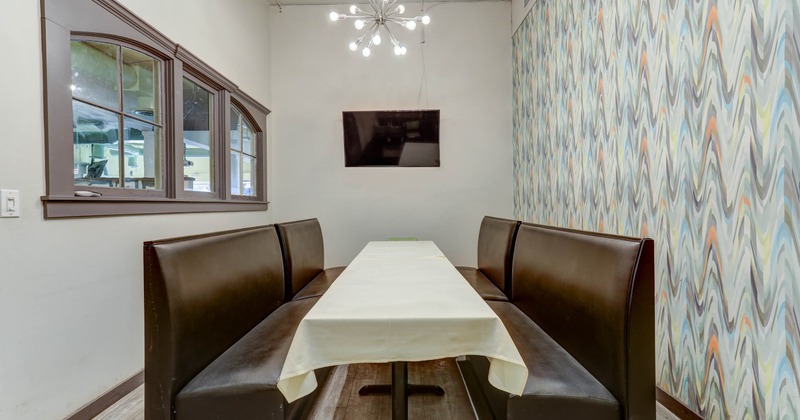 Private dining room with a white-covered table and dark leather booths