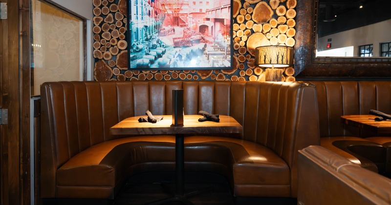 Interior, a brown leather booth with a wooden table and decorative wall