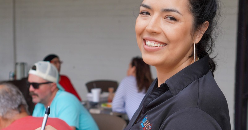 A server serves food to a couple of guests sitting in a booth