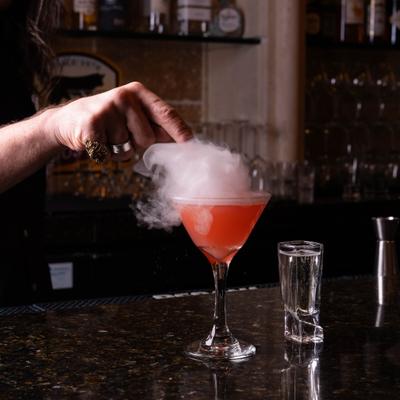 Cocktail in Nick and Nora glass being smoked on the bar counter.