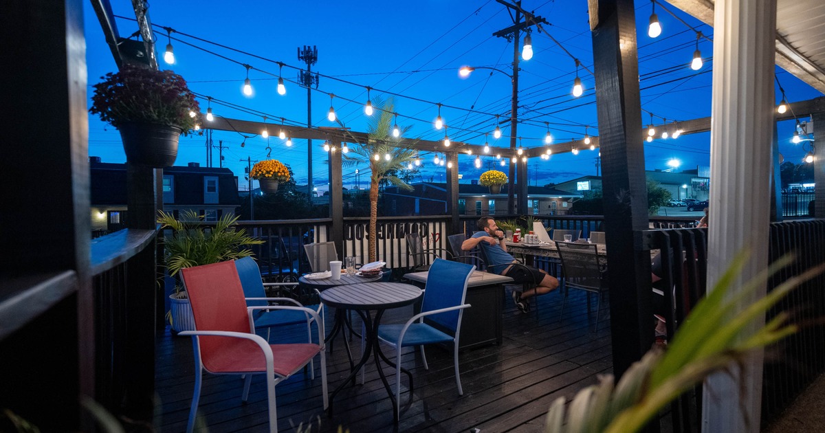 Outdoor patio at twilight with string lights, colorful chairs, and tables