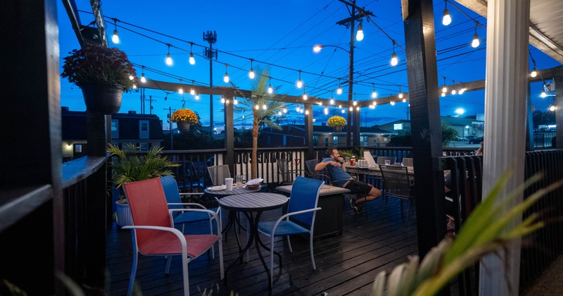 Outdoor patio at twilight with string lights, colorful chairs, and tables