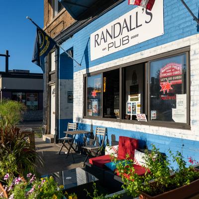 Exterior, restaurant front, patio, seating area, lavish plant decoration, painted brick wall.