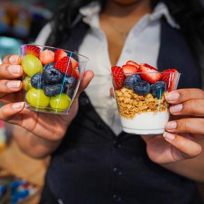 Server holding fruit cup and yogurt parfait with granola.