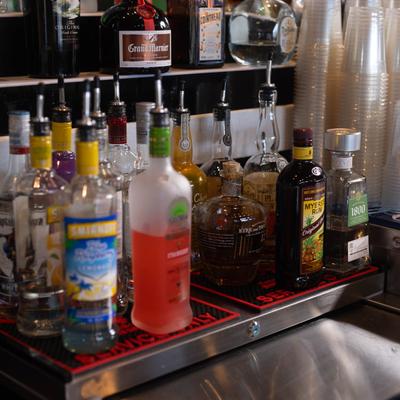 Assorted liquor bottles with pour spouts arranged on shelves.