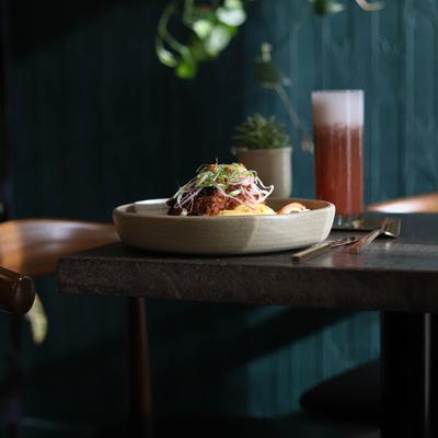 A colorful dish and a drink served on a dimly lit table.
