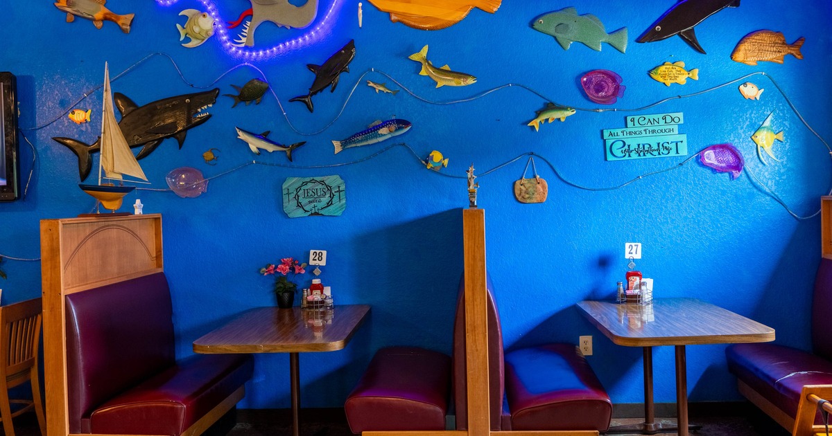 Interior, blue walls, fish decorations, red booth seating with wooden top tables