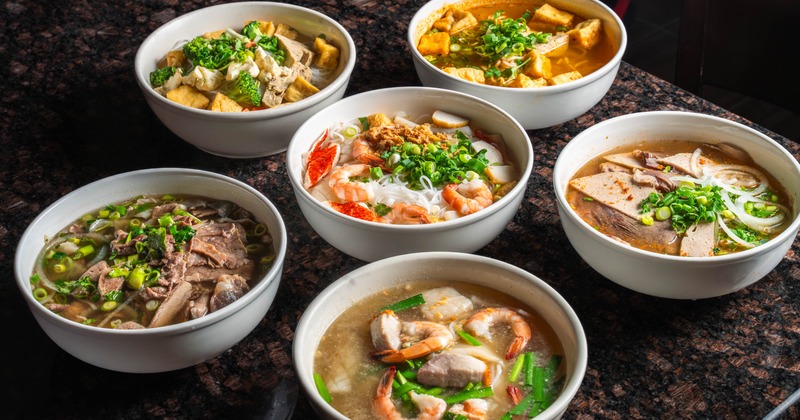 Assorted Vietnamese noodle soups and curry dishes on a table