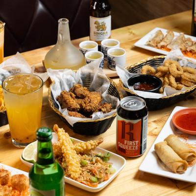 Assorted fried appetizers with assorted drinks on a wooden table.
