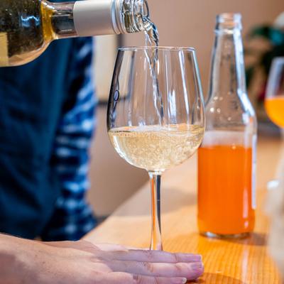 The barmen pours wine into the glass.