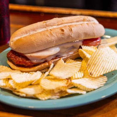 Pizza Hoagie featuring beef and pork patty with pizza sauce, cheese and a side of chips.