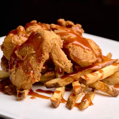 Chicken wings with fries, served.