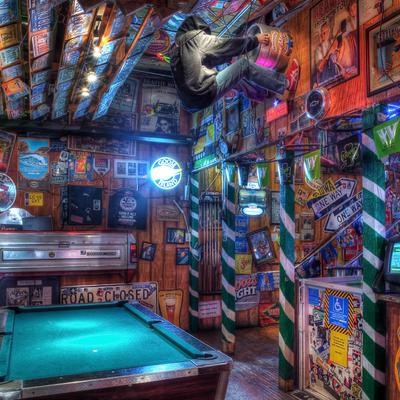 Interior packed with vintage signs and vibrant posters, a pool table and neon lights