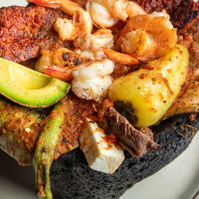Molcajete platter served in a sizzling, hot lava rock bowl, close-up.