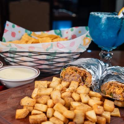 Burritos with pork, rice, beans, cilantro, onions, tomatillo sauce, and a side of potatoes.