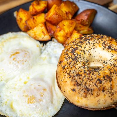 Over medium Eggs Breakfast with everything bagel and home fries potatoes.