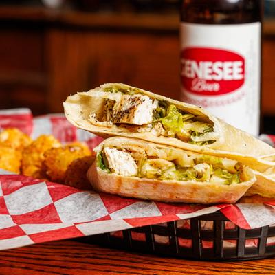 Grilled Cheese Caesar Wrap served with tater tots and a bottle of beer.