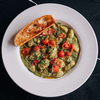 Gnocchi with pesto cream sauce, roasted tomatoes, Parmesan, and basil.