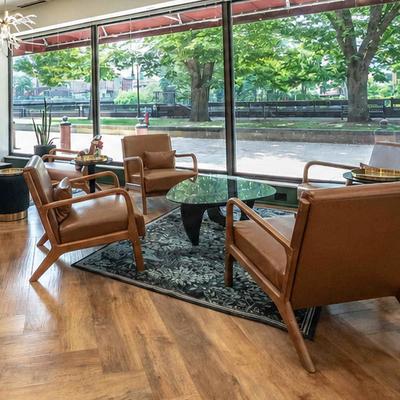 Interior featuring brown leather armchairs and a dark green accent wall with a neon sign.
