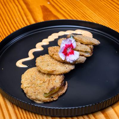 Fried green tomatoes with sauce drizzle and edible flower garnish.