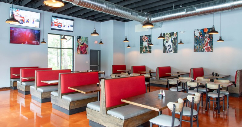 Interior, two rows of inline dining booths with lined up tables in the middle aisle, sports decor, TVs