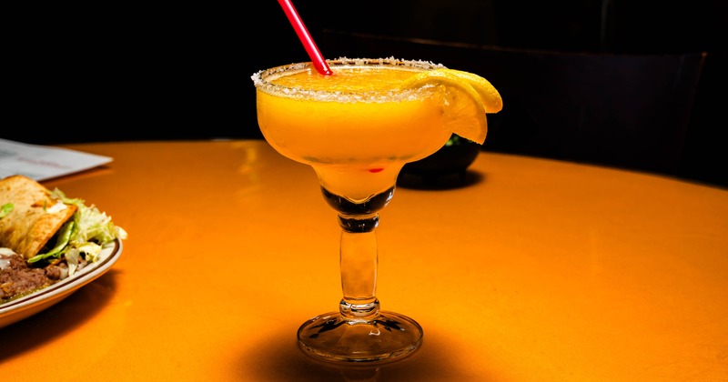 Frozen orange cocktail with citrus wedge and salted rim