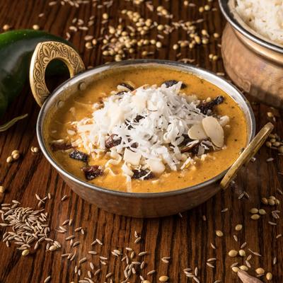 Creamy lamb korma topped with coconut shavings and nuts, served with rice.