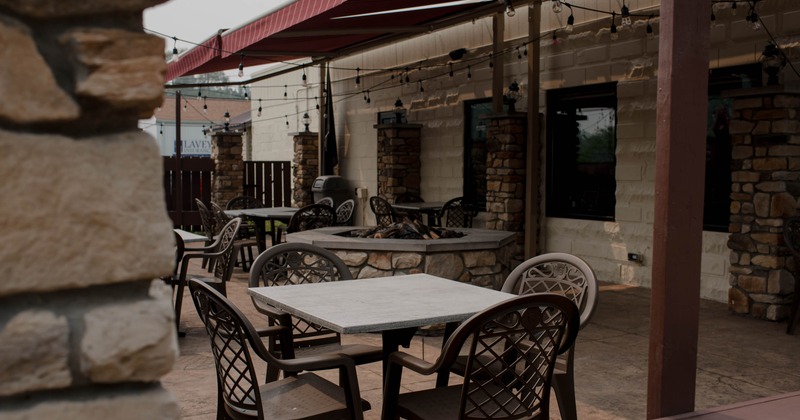 Outdoor patio featuring round tables and metal chairs under a red awning