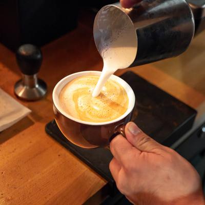 A barista decorating a latte with frothed milk.