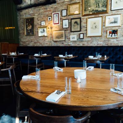 Tables ready for guests, banquette seating, drawings and pictures on a wall