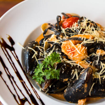 Black pasta with mussels tomatoes and grated cheese.