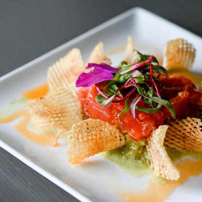 Tuna tartare with chips and colorful garnish, close-up.