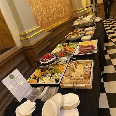 A long buffet table is covered with a black tablecloth and features various food items.