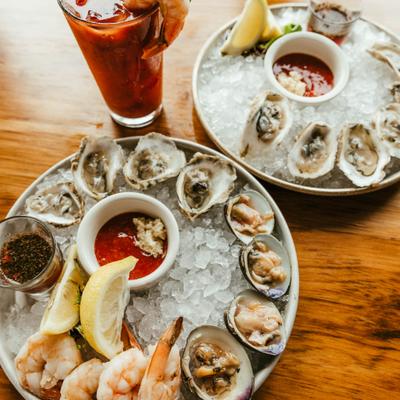 Seafood spread featuring oysters, clams and shrimp served on ice and a Bloody Mary.