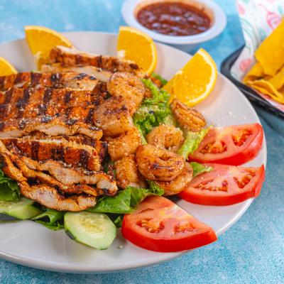 Spanish salad with grilled chicken, shrimp, lettuce, tomatoes, and orange slices.