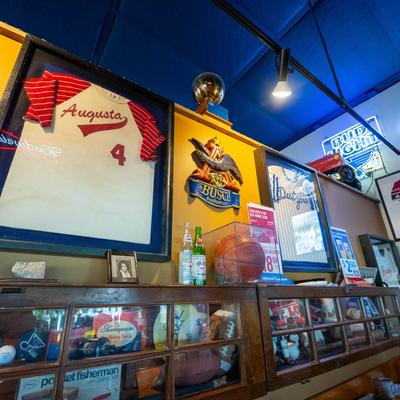 Sports memorabilia wall with framed jerseys, basketball, and beer signs.