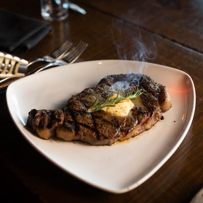 16 ounce rib eye steak topped with butter and rosemary sprig.