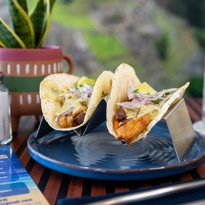 Two Peruvian style tacos served on a dining table.
