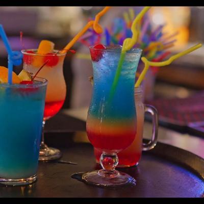Colorful cocktails on a tray, garnished with fruit slices and straws.