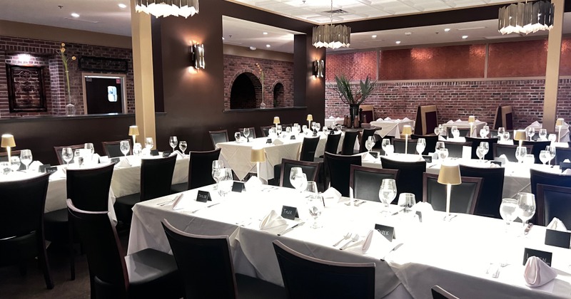 Wide view of the main ding room.  White table cloths and wine glasses set on tables.