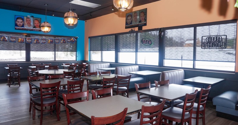 Interior of an empty restaurant with wooden tables, chairs, booth seating, pendant lights