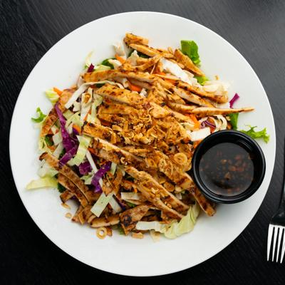 Overhead view of chicken salad with peanuts, cabbage, and fish sauce.