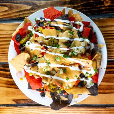 Pub Nachos topped with cheese sauce, olives, corn, jalapenos, pico de gallo and sour cream.