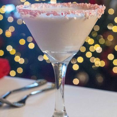 Festive martini glass with creamy white drink, rimmed with pink sugar.