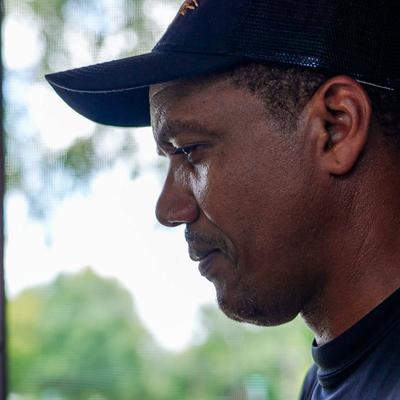 Close-up portrait of a person in a black cap outdoors.
