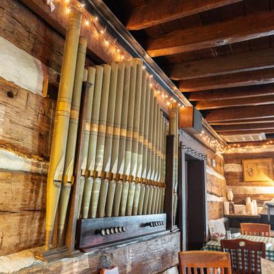 Wall-mounted pipe organ installed against a wood-paneled walls.