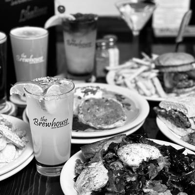 Black-and-white image showing multiple restaurant dishes arranged on a dining table.